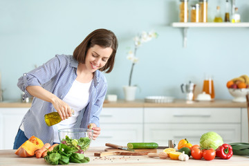 Young woman making salad in kitchen