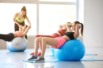 Young sporty women doing exercises with fitballs in gym