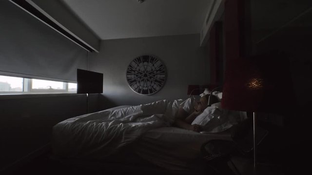 A young woman awakes in a bedroom when the window blind goes up automatically