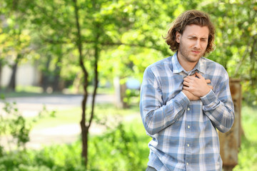 Young man suffering from pain in chest outdoors