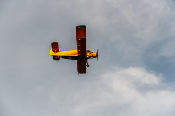 Small orange biplane airplane plane with propellers spraying crops with pesticides and herbicides...