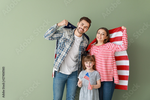 Happy young family with national flags of USA on color background