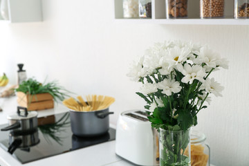 Vase with bouquet of flowers on counter in kitchen