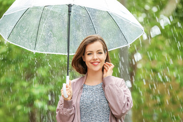 Beautiful young woman with umbrella outdoors on rainy day