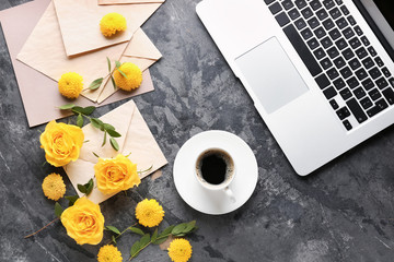 Beautiful composition with flowers, laptop, envelopes and cup of coffee on grunge background