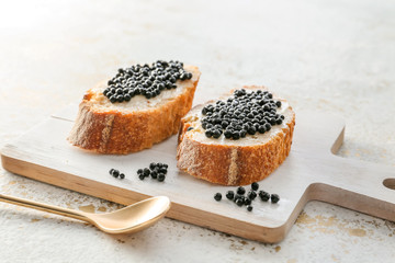 Sandwiches with black caviar on board