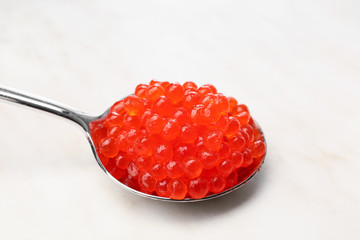 Spoon with red caviar on light background