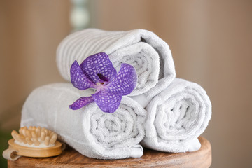 Rolled towels, flower and massage brush on table in spa salon