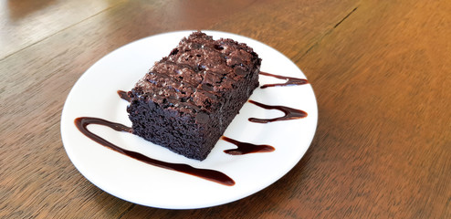 Chocolate brownie in white plate on wood table background