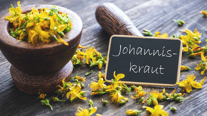 Johanniskraut Blüten in Holzmörser mit Schildchen und Stössel