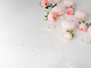 Fototapeta na wymiar Delicate buds of pink roses and airy marshmallows. Flat Lay. Copy space.