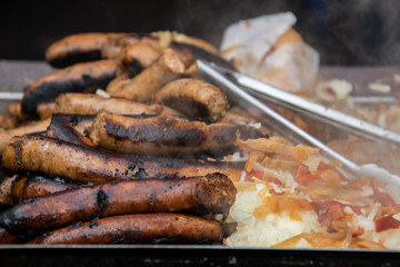 Pile of sausages and hotdogs on a hot grill that is smoking.