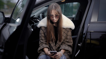 Obraz na płótnie Canvas Young woman using smartphone in car