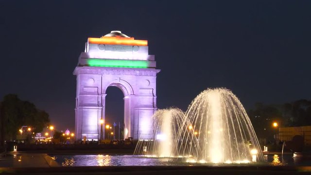 close up of a floodlit fountain and india gate with indian flag projected onto it at night in new delhi, india