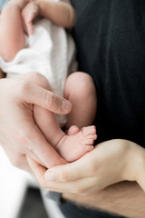 Little newborn baby, new life. Baby feet in the hands of parents. Child protection.