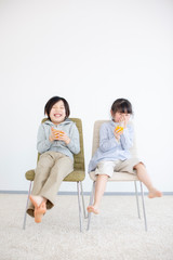 椅子に座りジュースを飲む子供