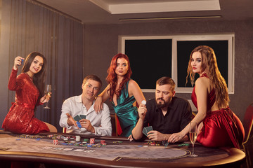 Group of a young rich friends are playing poker in casino.