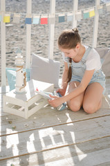 A young beautiful girl sits on the beach keeps toys and smile