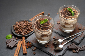 Classic tiramisu dessert in a glass on stone serving board on dark concrete background