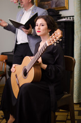 Fototapeta na wymiar Beautiful girl performs playing acoustic guitar in a black dress