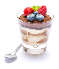 Classic tiramisu dessert with blueberries and raspberries in a glass isolated on a white background with clipping path