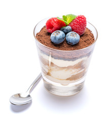 Classic tiramisu dessert with blueberries and raspberries in a glass isolated on a white background with clipping path