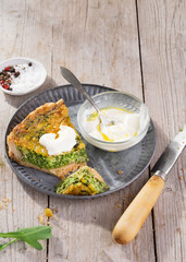 Slice Quiche on a plate with arugula, onion, spinach, mozzarella, feta and sauce on rustic background, top view, space for Homemade, traditional french quiche pie.