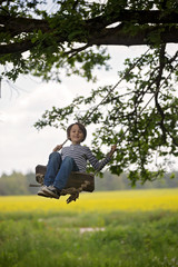 Sweet child, preteen boy, swinging on a wooden swing