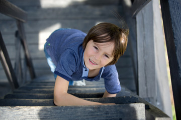 Child, preteen boy, sitting on wooden stairs