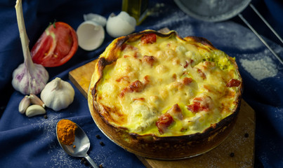 delicious open French cake with chicken cauliflower onion garlic egg cream tomato pepper turmeric baked in oven on table blue cloth sieve flour