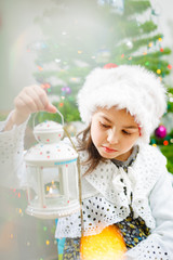 Nice girl in a Christmas hat with a candlestick in her hands, Fur-tree