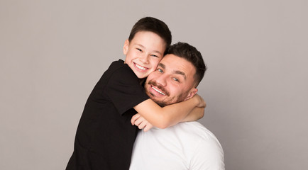 Fototapeta premium Cheerful boy hugging with his father, happy family portrait