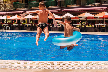 Kids jump into the outdoor pool on vacation