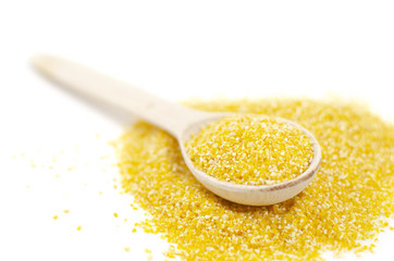 Yellow corn grits are in a wooden spoon on a white background