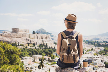 Traveler girl enjoying vacations in Greece. Young woman wearing hat looking at Acropolis in Athens. Summer holidays, vacations, travel, tourism concept.