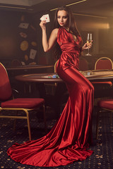 Young charming female is posing at a poker table in vip casino.