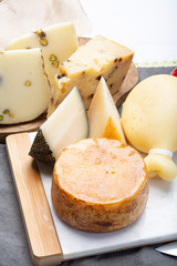 Variety of Italian pecorino and provolone cheeses, yellow aged, with black peppers from Nebrodi, white Il Palio and black molarotto, close up