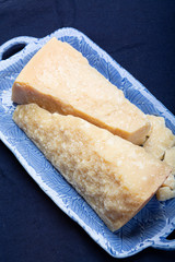 Italian original aged Parmesan cheese in two pieces served on blue plate close up
