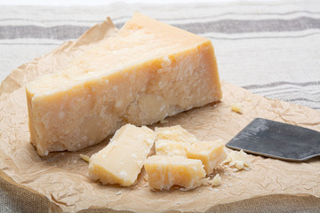 Piece of Italian original aged Parmesan cheese and cheese knife close up