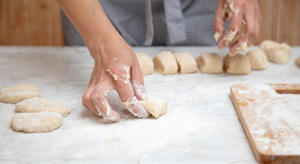 The hostess cuts the dough in the kitchen