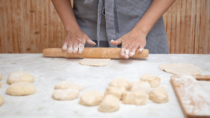 Girl rolls the dough in the kitchen