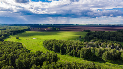 Obraz premium Aerial shot. Amazing green valley with oncoming thunderstorm clouds on bright summer day