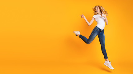 Fototapeta na wymiar Joyful Woman Jumping And Pointing At Copy Space