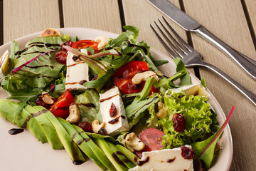Tasty and healthy salad with arugula, brie, cheese, avocado, cherry tomatoes, dry cranberry and cashews. Top view. The flat lay. Banner