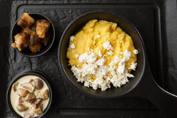Typical Ukrainian dish polenta - Banosh with cheese and lard. Ukrainian cuisine. maize porridge with bacon, cracklings and cheese Corn porridge in plate on wooden background.