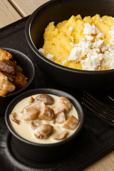 Typical Ukrainian dish polenta - Banosh with cheese and lard. Ukrainian cuisine. maize porridge with bacon, cracklings and cheese Corn porridge in plate on wooden background.
