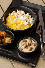 Typical Ukrainian dish polenta - Banosh with cheese and lard. Ukrainian cuisine. maize porridge with bacon, cracklings and cheese Corn porridge in plate on wooden background.