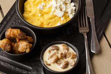 Typical Ukrainian dish polenta - Banosh with cheese and lard. Ukrainian cuisine. maize porridge with bacon, cracklings and cheese Corn porridge in plate on wooden background.