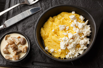 Typical Ukrainian dish polenta - Banosh with cheese and lard. Ukrainian cuisine. maize porridge with bacon, cracklings and cheese Corn porridge in plate on wooden background.