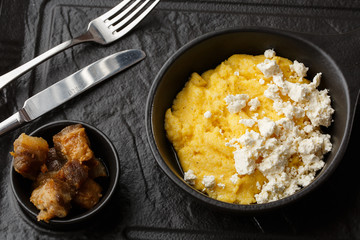 Typical Ukrainian dish polenta - Banosh with cheese and lard. Ukrainian cuisine. maize porridge with bacon, cracklings and cheese Corn porridge in plate on wooden background.